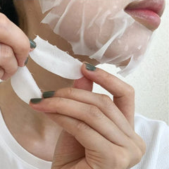 A close-up of a person peeling a translucent, semi-occlusive facial sheet mask from their cheek and jawline. -KAO Curél Moist Repair Sheet Mask 4PCS | Sensitive Skin Hydration-THE COSMETIC STORE NZ