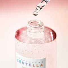 Bottle of Cica Centella serum with dropper on a pink background