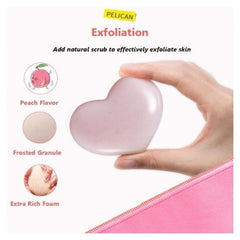 A hand holds a heart-shaped pink exfoliating scrub bar labeled PELICAN. The image includes marketing text reading 'Exfoliation,' 'Add natural scrub to effectively exfoliate skin,' and feature callouts for 'Peach Flavor,' 'Frosted Granule,' and 'Extra Rich Foam,' with a pink pouch shown at the bottom right.Pelican Soap Attractive Hip Care Soap 80g | Butt Whitening & Scrub- The Cosmetic Store New Zealand