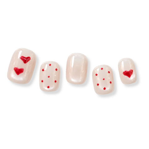 false press-on nails arranged in two rows on a plain white background. The nails have a glossy pale pink base with red heart and dot designs in varying amounts.