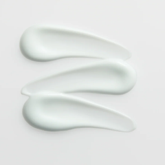 Three smears of white cream on a light gray background