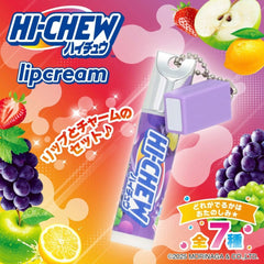 Morinaga Hi-Chew Lip Cream in purple grape flavor, shown as a lip-shaped gum stick with a small purple cap and silver metal ring, surrounded by fruit illustrations including strawberries, grapes, apple, and lemon on a colorful pink and orange background.-THE COSMETIC STORE NZ