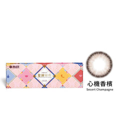 A box of STAR SHINE# COLOR DAY# SECRET CHAMPAGNE contact lenses with a single contact lens displayed in front of the box.