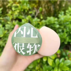 Hand holding a green face mask with white text against a blurred green background