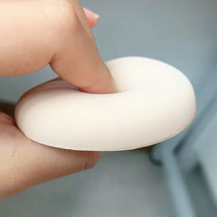 Hand holding a white silicone ring against a blurred background