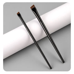 Two black makeup brushes on a gray background