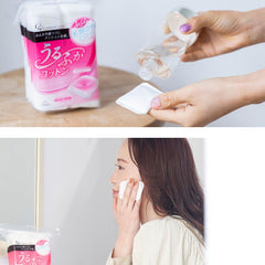 Cotton pad being used on a woman's face with a pink packaging of cotton pads in the background.