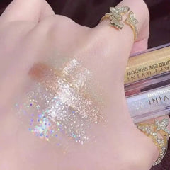 Hand with glittery makeup and a gold ring, with a makeup product in the background