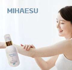Woman applying a bottle of MIHAESU skincare product to her arm on a white background