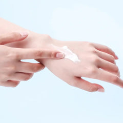 Person applying cream to their hand on a light blue background