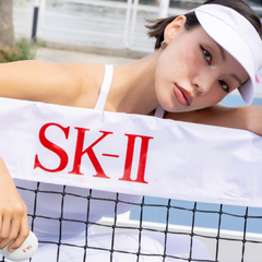 Woman holding an SK-II branded towel on a tennis court-SK-II Genoptics CC Primer bottle -tone up primer- available at The Cosmetic Store New Zealand