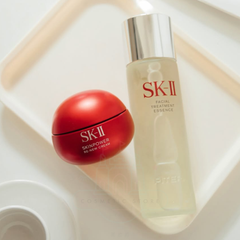 SK-II skincare products including a red cream and a facial treatment essence on a light background