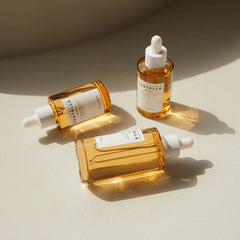 Three bottles of Santela skincare serum on a beige background