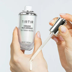 TIRTIR Ceramic Milk Ampoule with a dropper held by hands against a light gray background