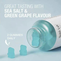 A clear bottle of gummy candies with a white label, shown lying on its side with two light aqua gummies spilled out. Large text reads 'GREAT TASTING WITH SEA SALT & GREEN GRAPE FLAVOUR' and '2 GUMMIES DAILY'.- Unichi Teddi Lab Hair Boost Gummy Plus 60s-The Cosmetic Store
