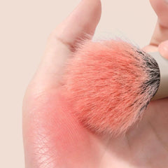 Makeup brush with pink blush on a beige background