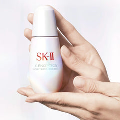 Hand holding an SK-II Genoptics skincare bottle against a light background