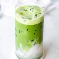 Glass of iced green tea with milk on a white background