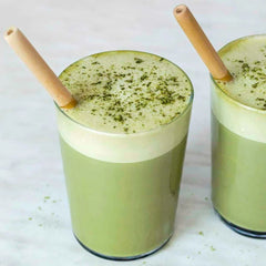 Two green smoothies with bamboo straws on a light background