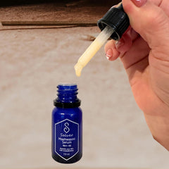 Hand holding a dropper over a blue serum bottle labeled 'Salmi Mawwsoo Serum' on a neutral background.