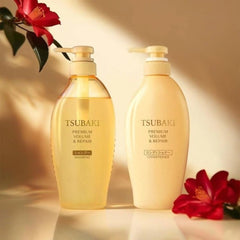 Two bottles of Tsubaki shampoo and conditioner with red flowers on a warm background