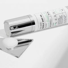 Skincare product with a silver cap and white body on a light gray background