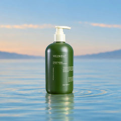 Wildheke Natural Conditioner Olive and Kawakawa 500ml pump bottle at The Cosmetic Store NZ-A dark green pump bottle of Wild Hecke Conditioner Olive & Reparative hair conditioner floating on calm water with a soft blue sky and distant mountains in the background.