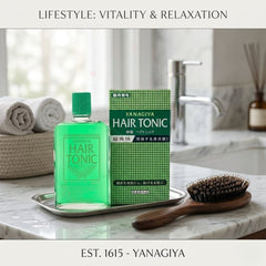 Yanagiya hair tonic 240ml - YANAGIYA - The Cosmetic Store New Zealand-A bottle of Yanagiya Hair Tonic with its green packaging box, displayed on a silver tray on a marble countertop in a bathroom setting. A wooden hairbrush and rolled towels are also visible in the background, with text banners at the top and bottom reading 'LIFESTYLE: VITALITY & RELAXATION' and 'EST.